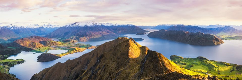 Roys Peak at sunrise above Lake Wānaka, New Zealand, with snowcapped mountains and islands in the lake beyond