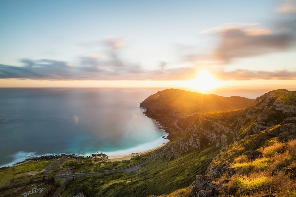 Two minute exposure of Makapuʻu Beach and the lighthouse point at sunrise, clouds streaked across the sky